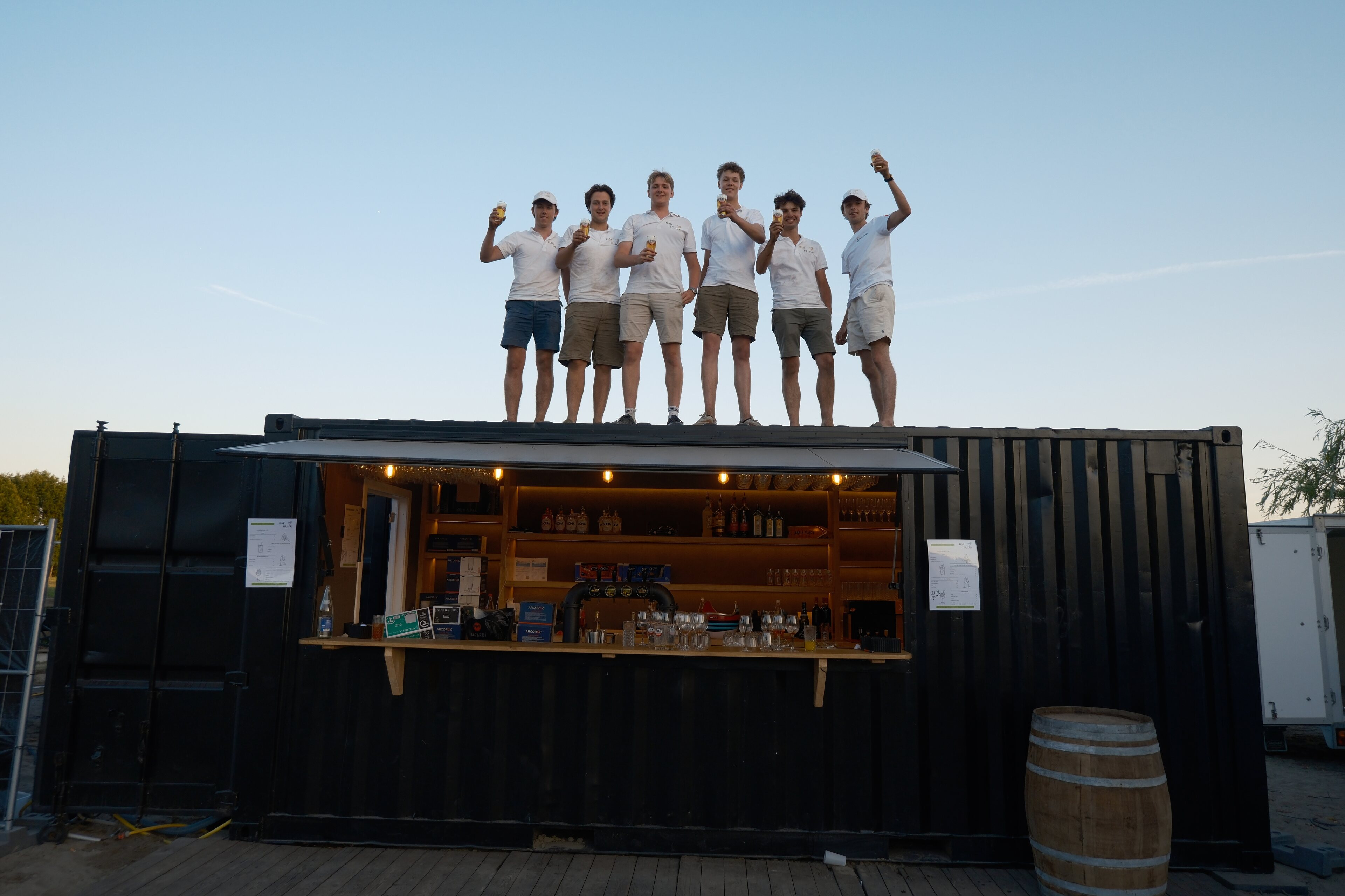 Het team van Bar à Place op het dak van de mobiele containerbar bij zonsondergang